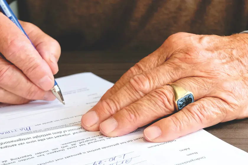 Hand unterschreibt ein Vorsorgedokument
